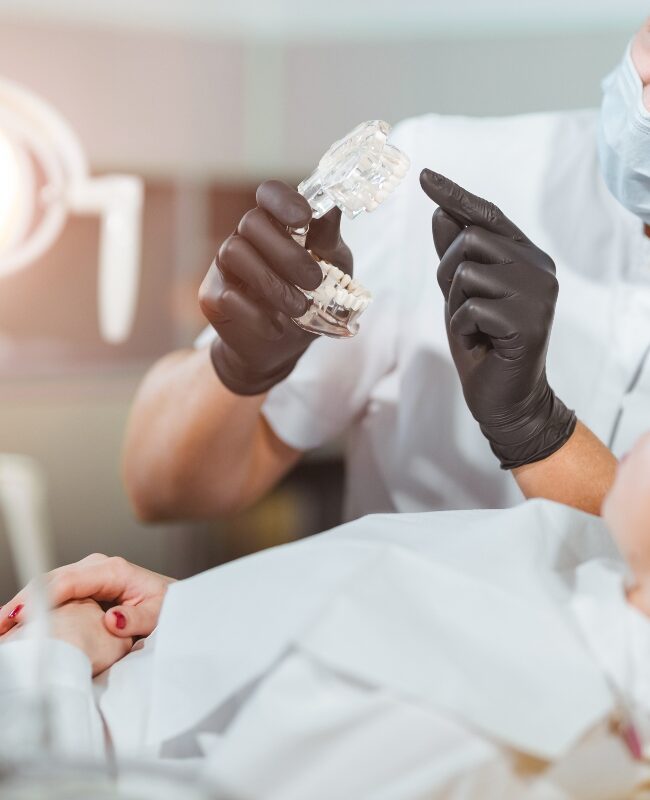dentist holding dental implant model