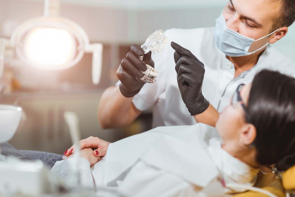 dentist holding dental implant model